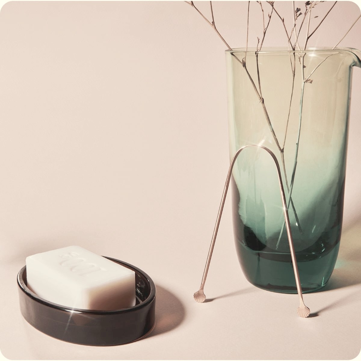 Gratte-langue en cuivre dans une salle de bain, à côté d’un savon et d’un vase