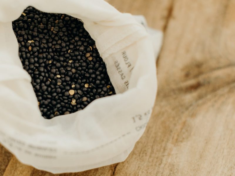 Lentilles béluga dans un sac à vrac en coton posé sur une table en bois